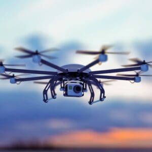 Black drone with camera flying in sky.